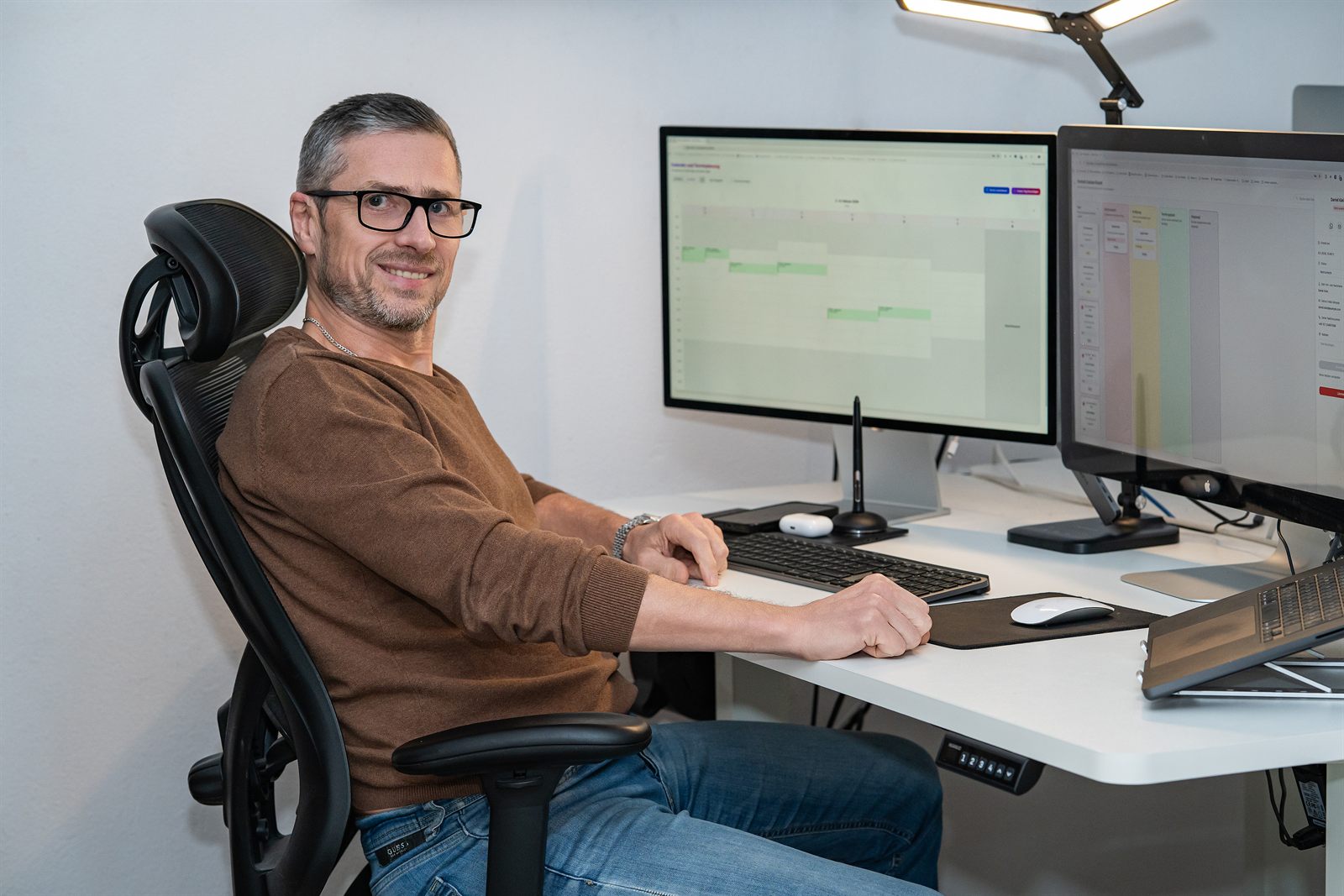 Viktor Obholz am Schreibtisch mit Belegungskalender und Auswertung auf zwei Monitoren