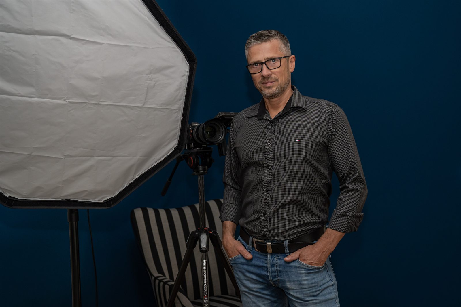 Viktor Obholz im Studio vor blauem Hintergrund neben Kamera und Softbox
